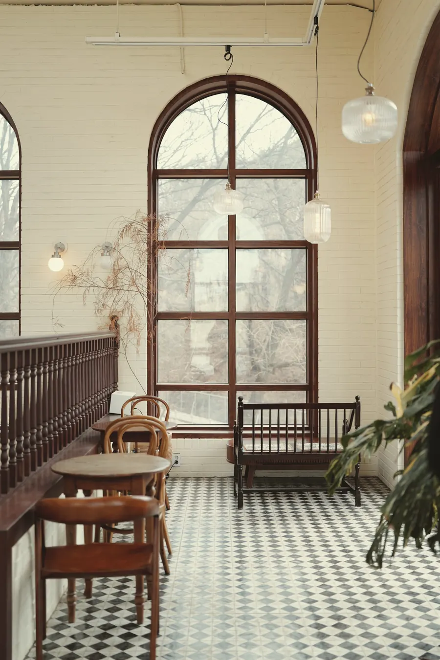 A café with tall arched windows, a checkered floor and bentwood chairs