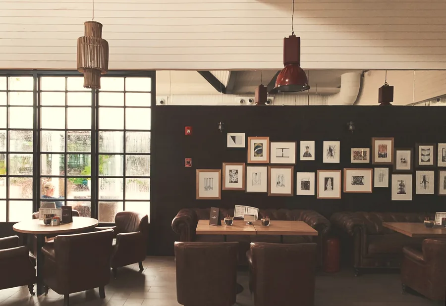 A bright café with leather armchairs and a wall of framed prints