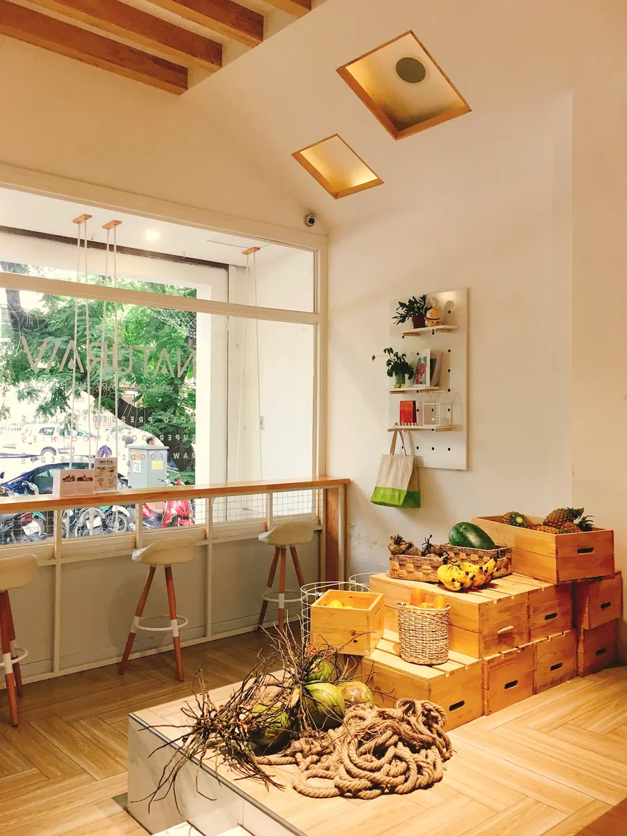 A sunlit café corner with plants, wooden crates and a window seat
