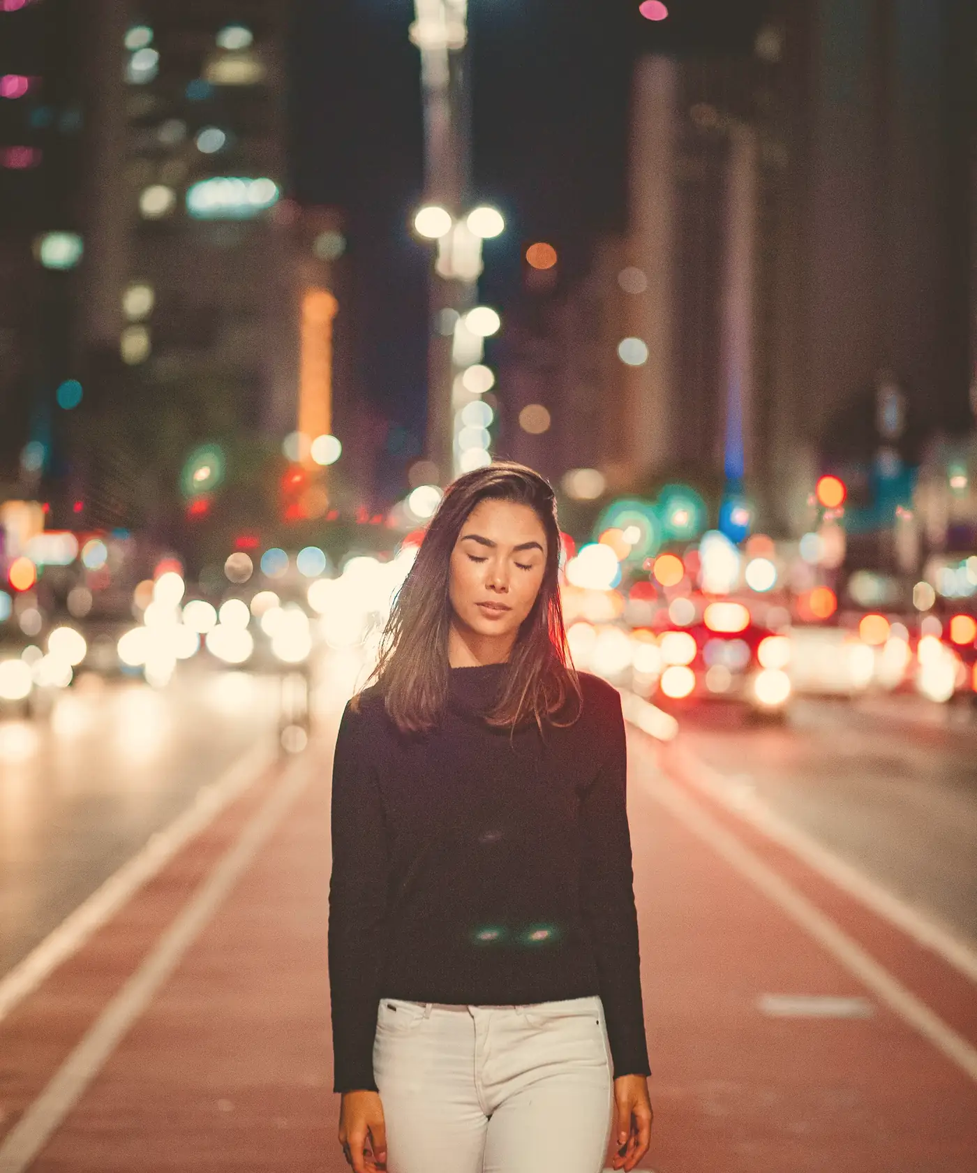 A woman walking home along a lit city street at night
